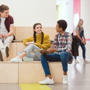 high school students sitting in lounge zone at school corridor